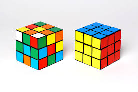 De ontknoping de oplossing De ontknoping: Rubiks kubus voor de oplossing. Twee kubussen. Eentje met kleuren door elkaar. De ander met alle kleuren op hun eigen zijde van de kubus.