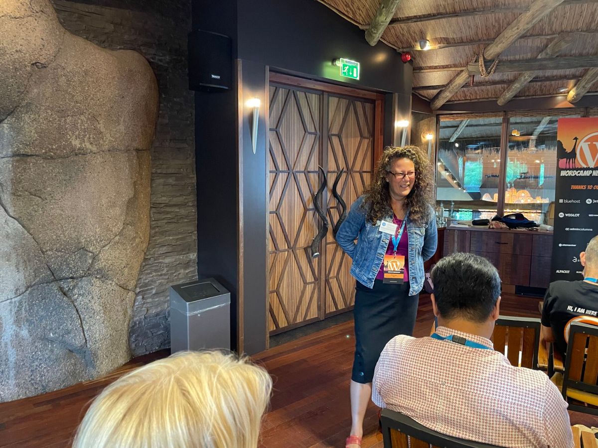 Maureen lachend tijdens workshop storytelling met handen op de rug. In Burgers Bush complex tijdens WordCamp Nederland.